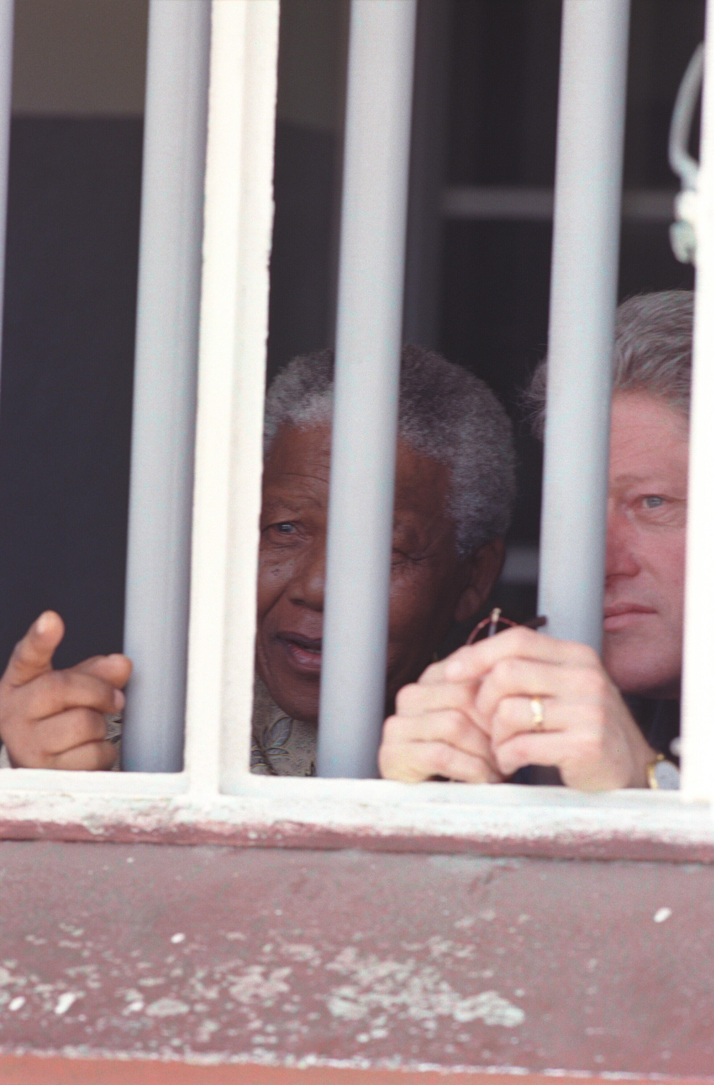 President Clinton and President Nelson Mandela stand behind bars in the Cell Block B in the Robben Island prison that once held Nelson Mandela. 