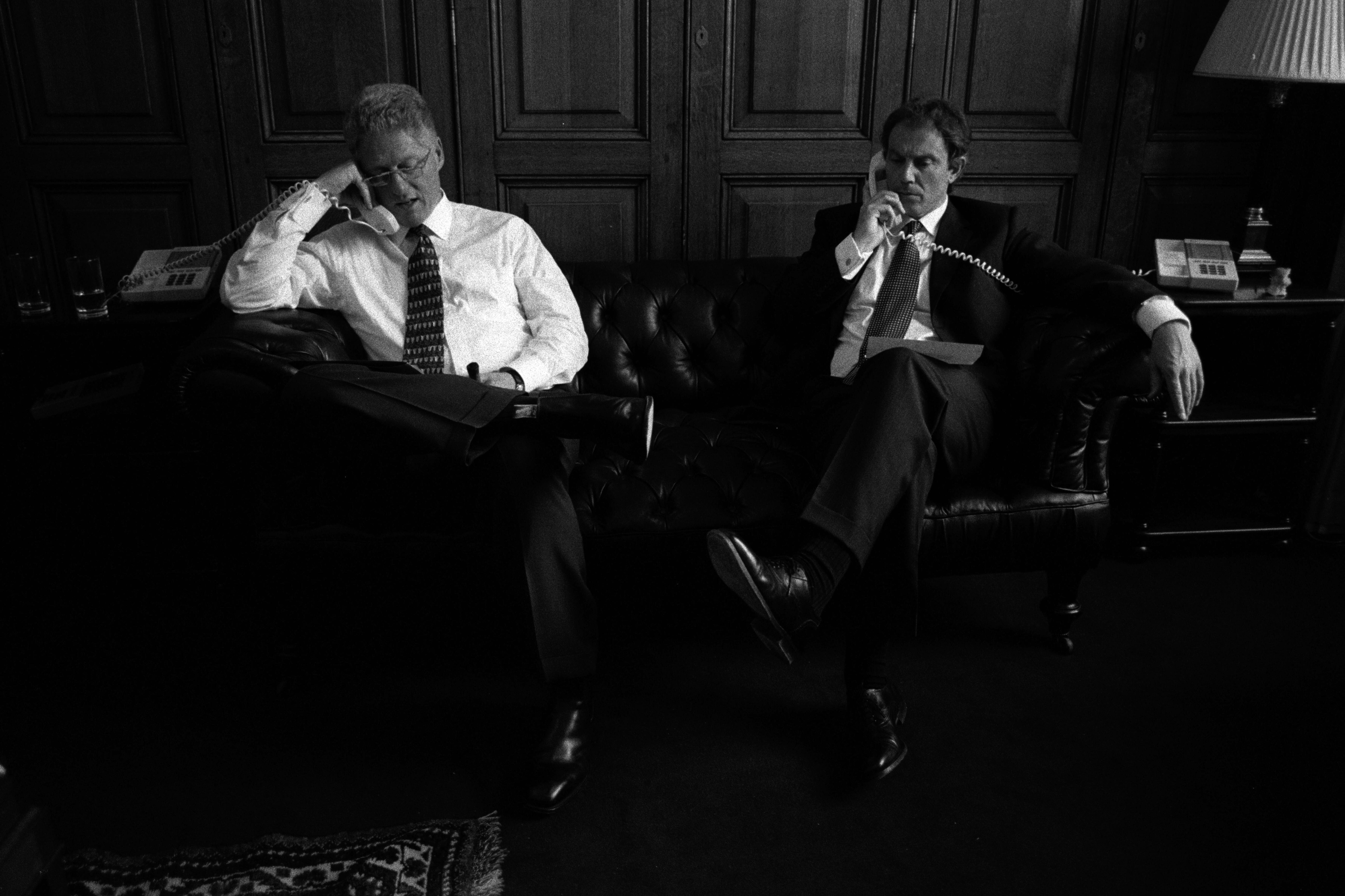 Black and white photo of President Clinton and Prime Minister Tony Blair of the United Kingdom talking on telephones at the Foreign Ministry, 10 Downing Street in London