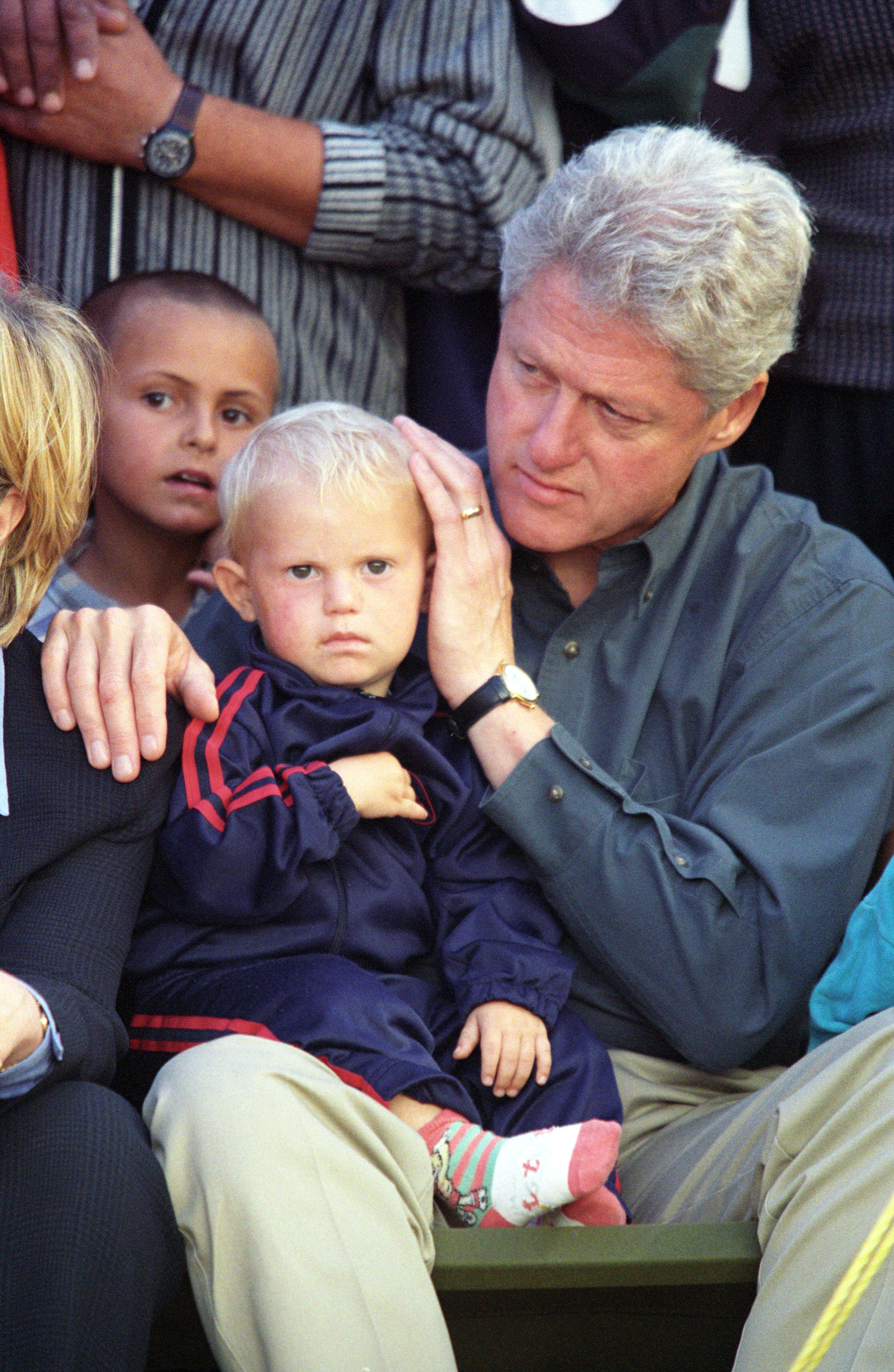 Boy sits on President Clinton's lap. President Clinton comforts a young Kosovar refugee at Stenkovic 1 Refugee Camp near Skopje, Macedonia, August 22, 1999, Photographer: William Vasta.