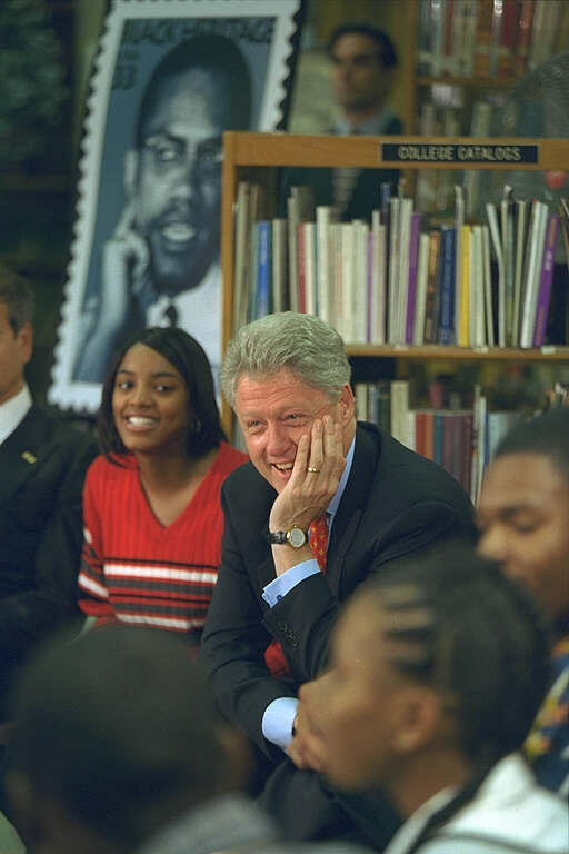 President Clinton sits with his face resting on his hand in an informal meeting with Project graduate students.