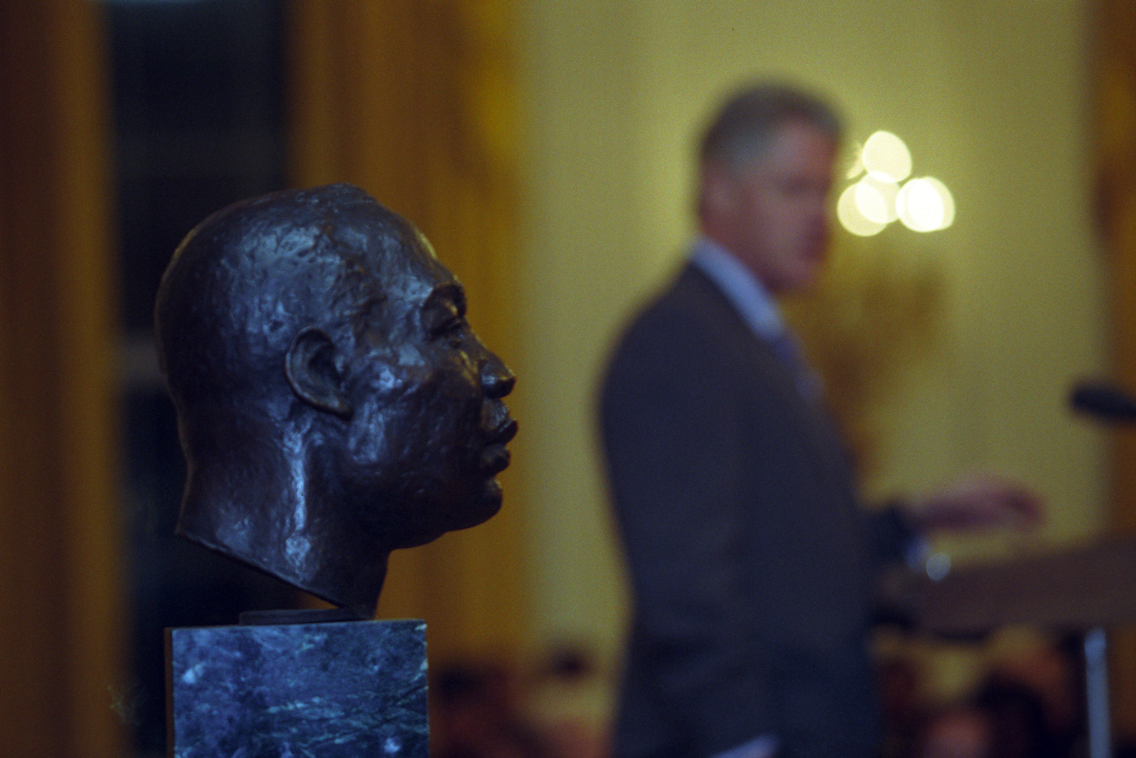 President Clinton delivers remarks in the East Room prior to his Radio Address. A bust of Martin Luther King, Jr. is on stage near the President