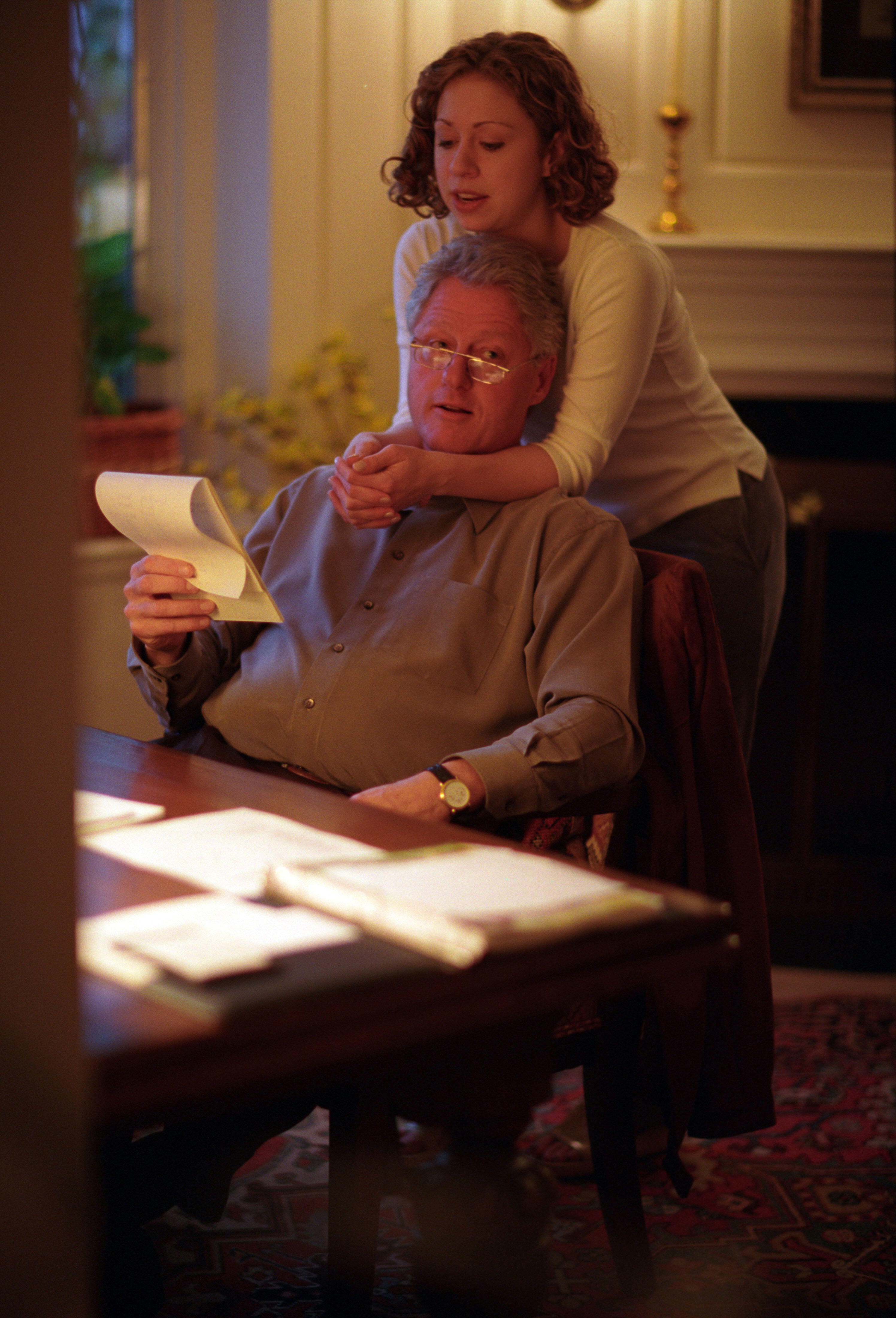 Chelsea Clinton wraps her arms around her Father President Clinton while he is seated at his home office desk in Chappaqua