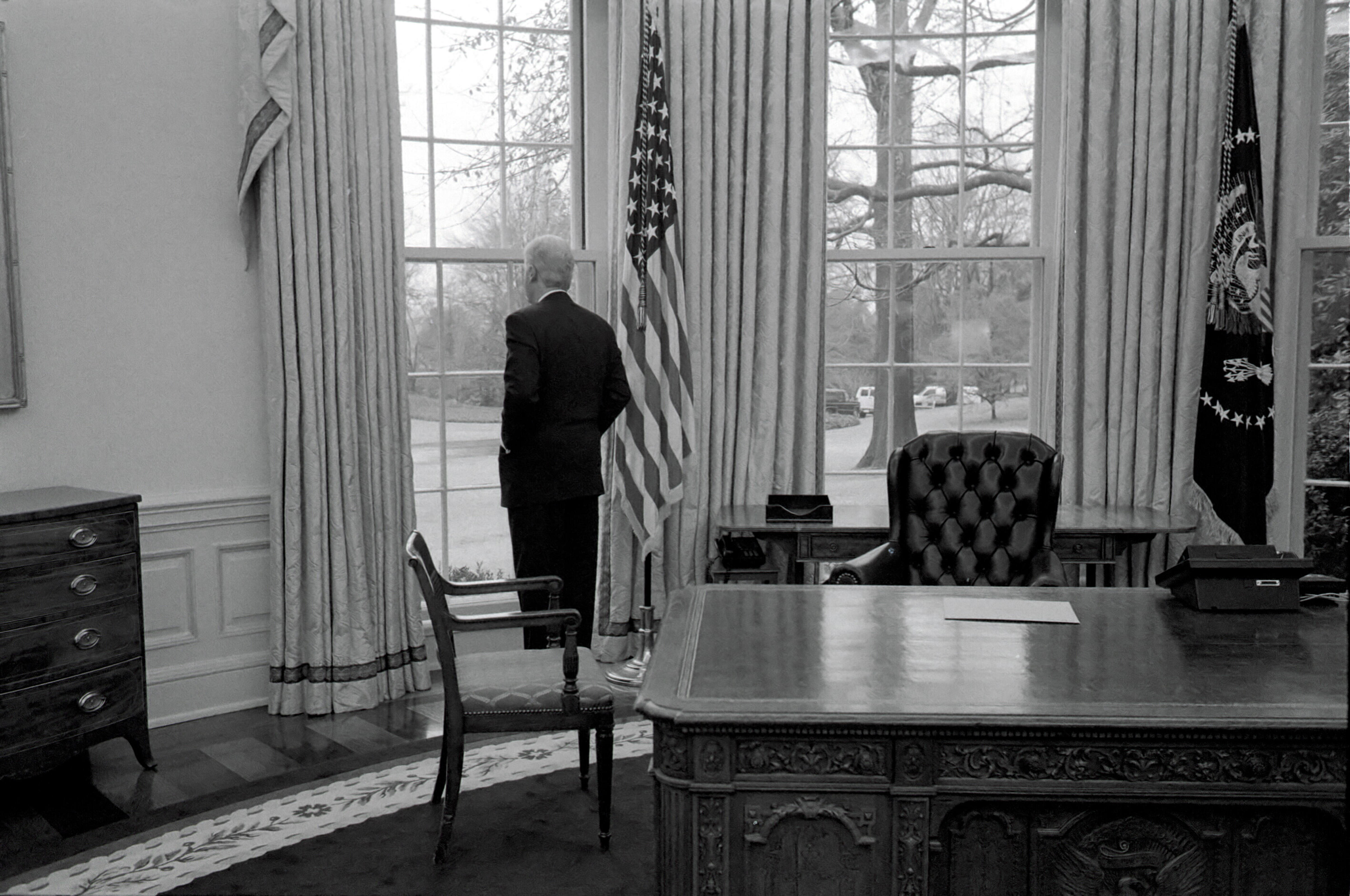 President Clinton stands alone, looking out of a window in the Oval Office, on his final day as President of the United States,